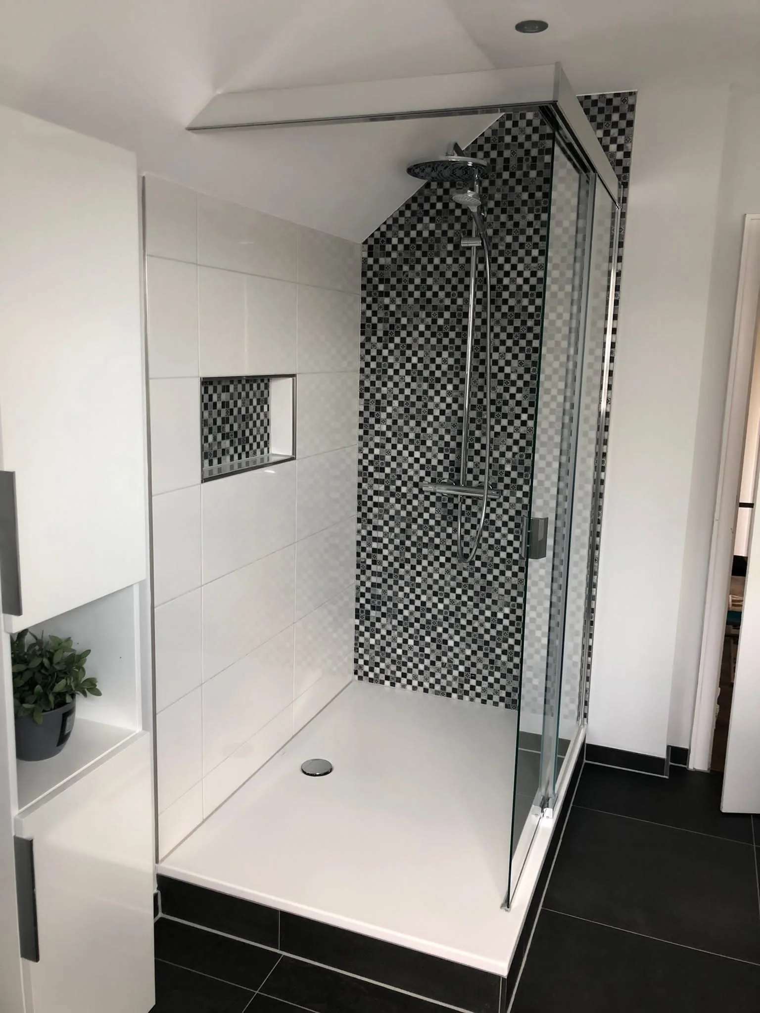 Eckdusche mit schwarz-weißer Mosaikrückwand und Nische unter der Dachschräge