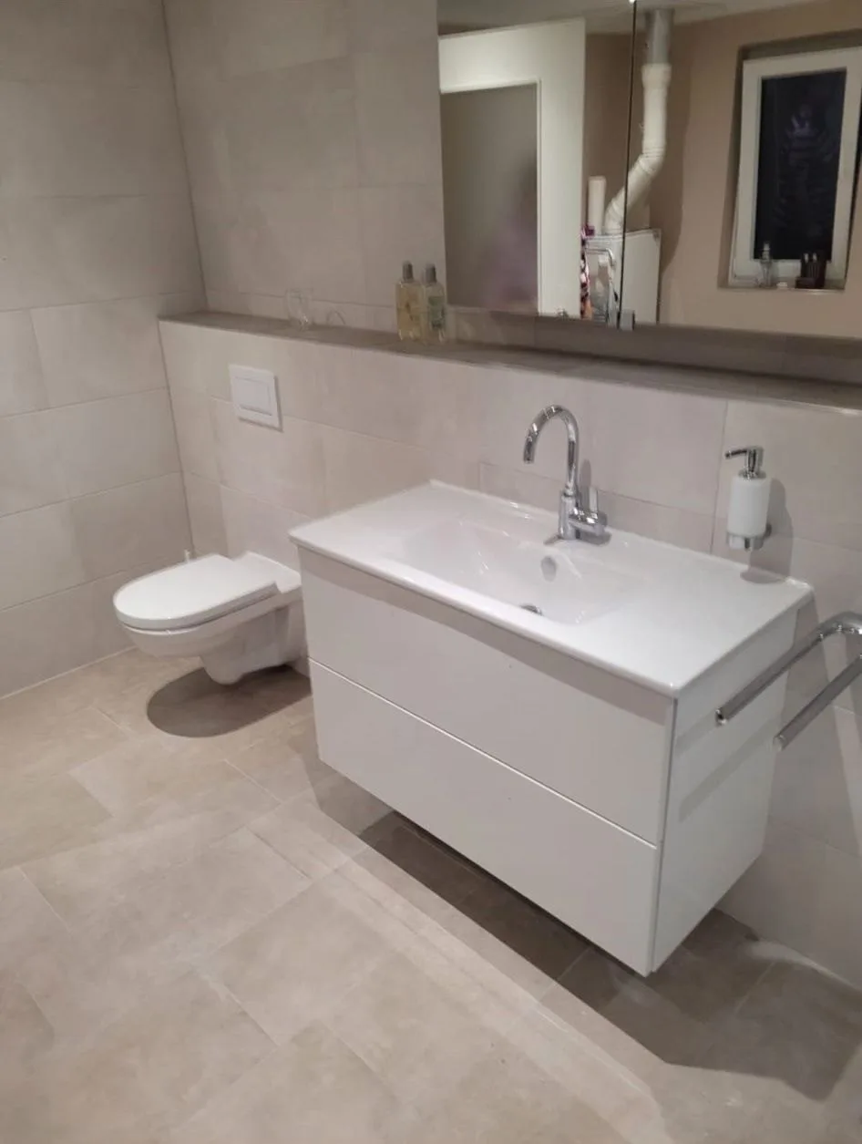 Helles Bad mit Waschtisch und Unterschrank, Wand-WC und Ablage vor einem großen Spiegel