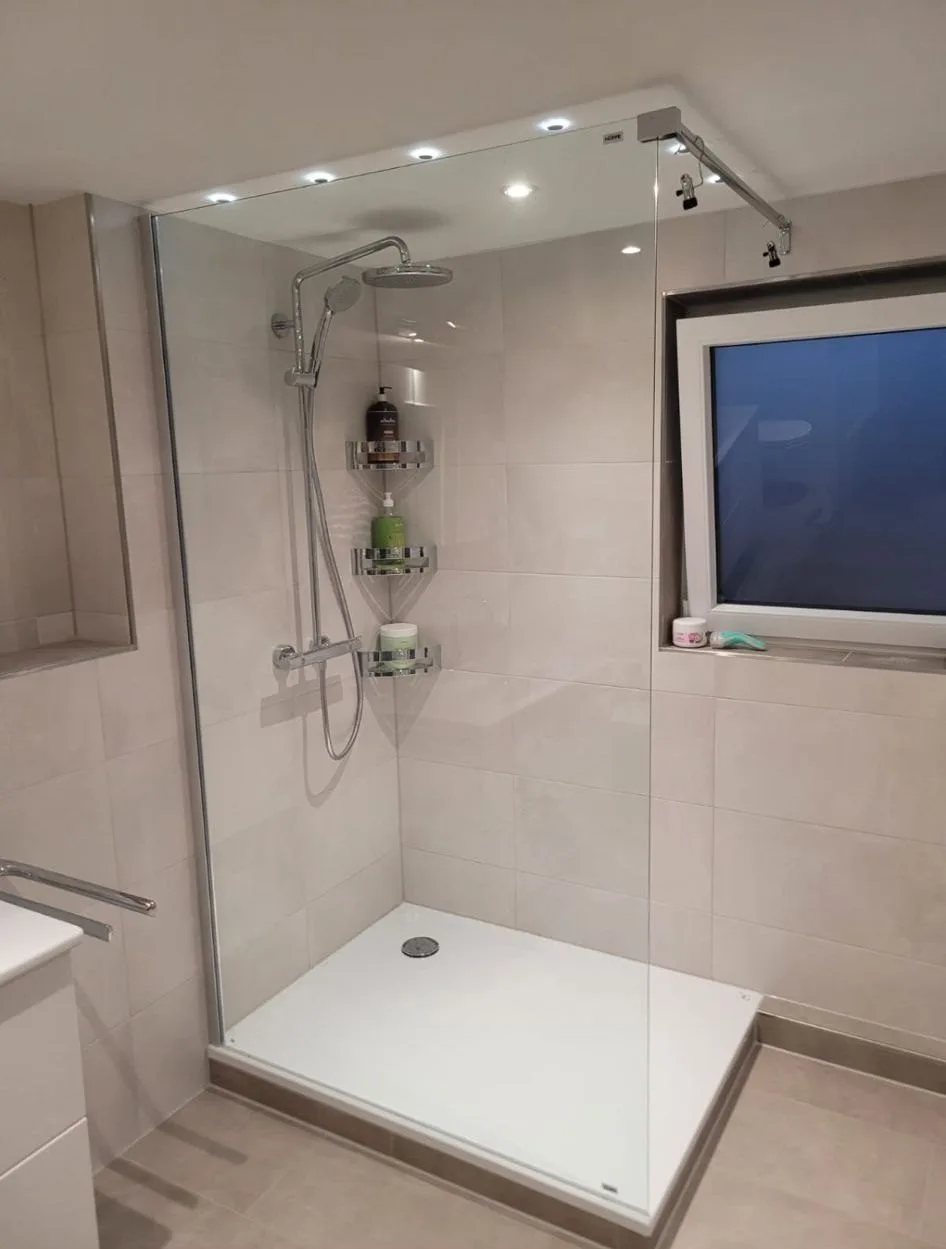 Walk-in-Dusche mit Glaswand, Regenbrause und Deckenspots neben einem Fenster